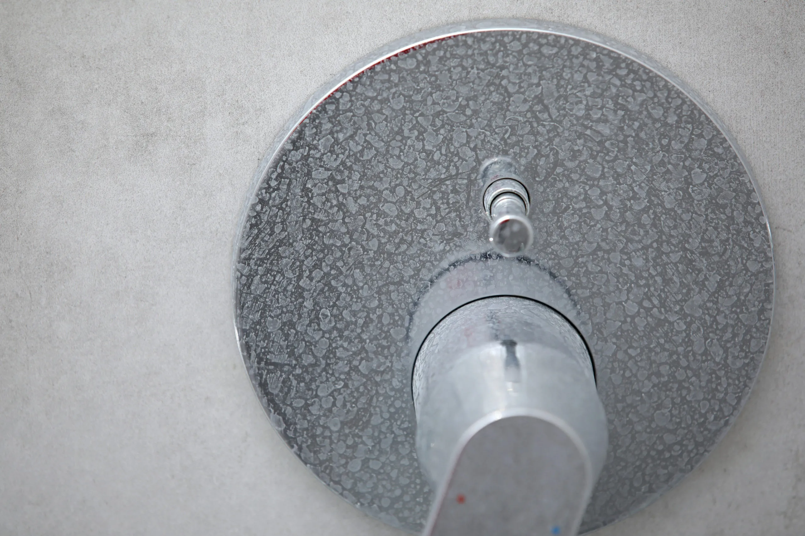 Limescale buildup around a shower fixture caused by hard water